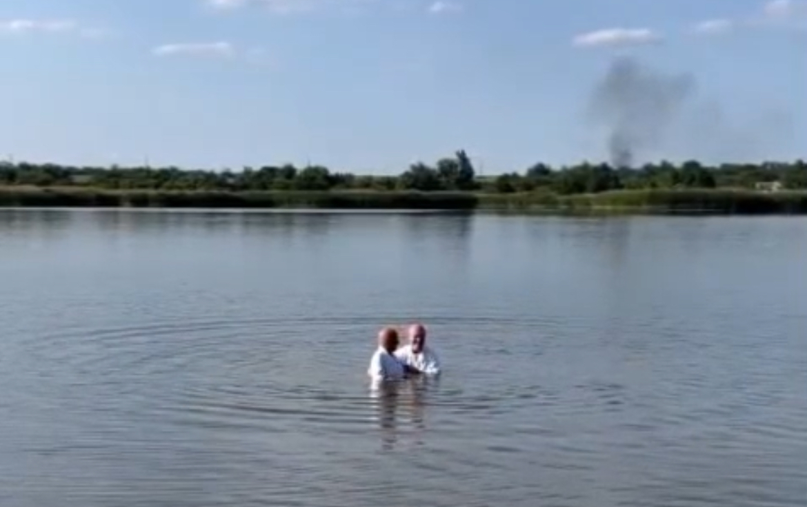 Водное крещение под звуки взрывов — видеофакт